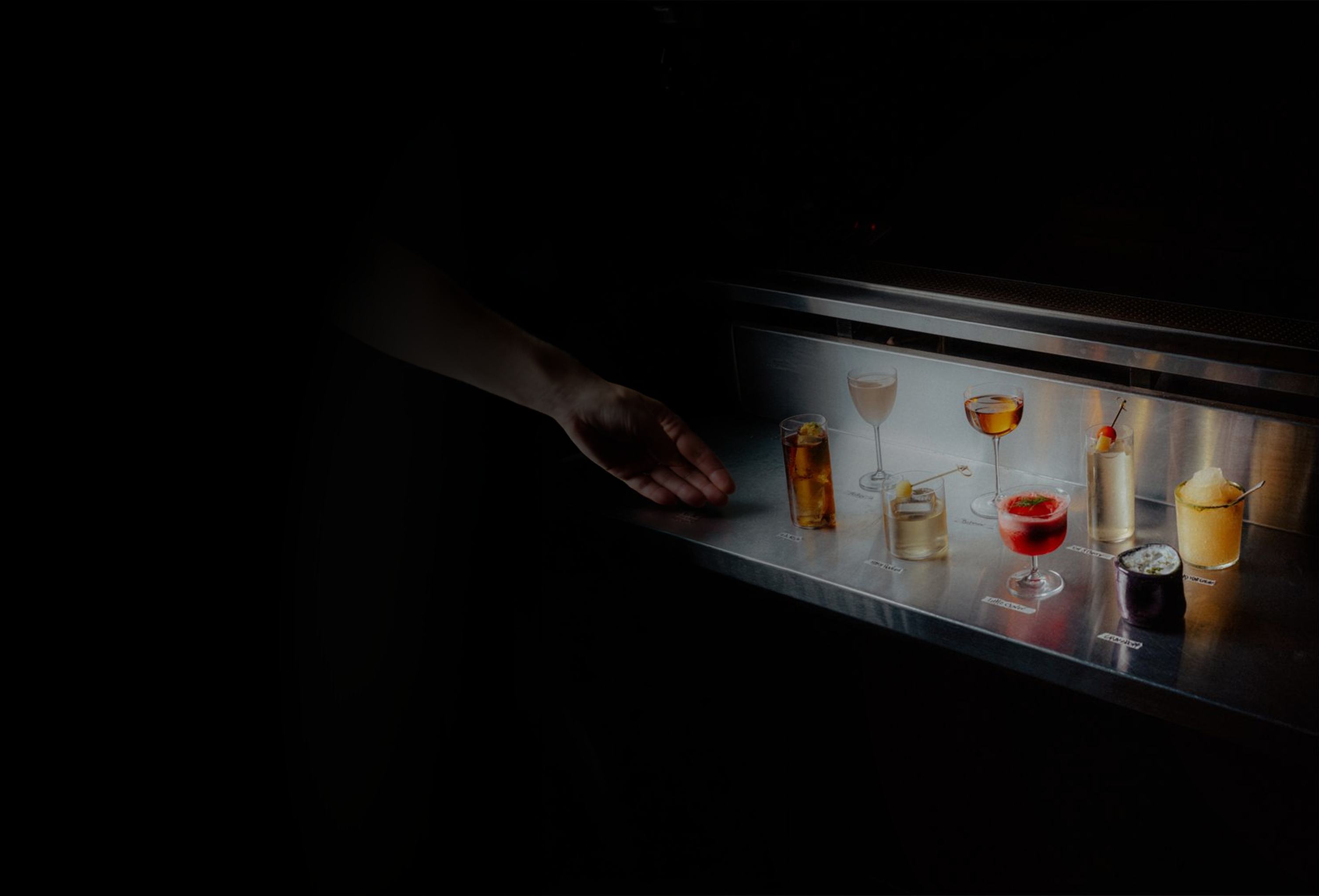 A row of cocktails lit on a bar counter